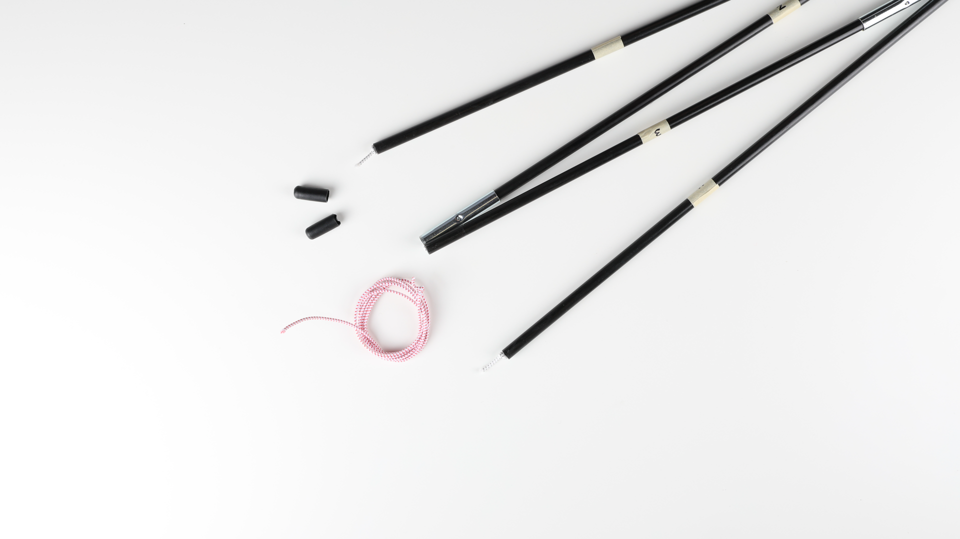 Disassembled black tent poles poles with two black caps. The newly installed shock cords tied into a knot is visble on both tent pole ends. A coil of red and white shock cord on a white background.